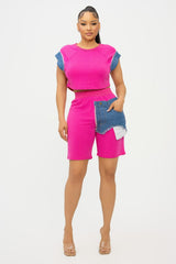 Woman wearing a bright pink short set with denim accents on a white background