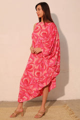 Woman wearing a pink patterned dress against a beige wall.