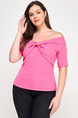 Woman wearing a pink off-shoulder top with a bow detail on a white background