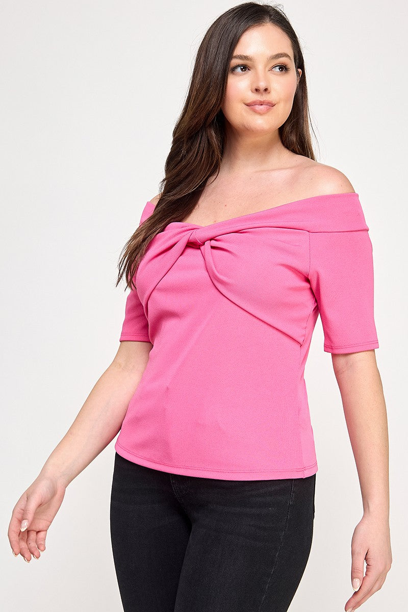 Woman wearing a pink off-shoulder top with a knot detail on a white background