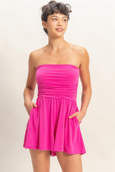 Woman wearing a bright pink strapless romper against a plain background