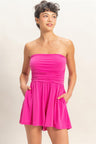 Woman wearing a bright pink strapless romper against a plain background
