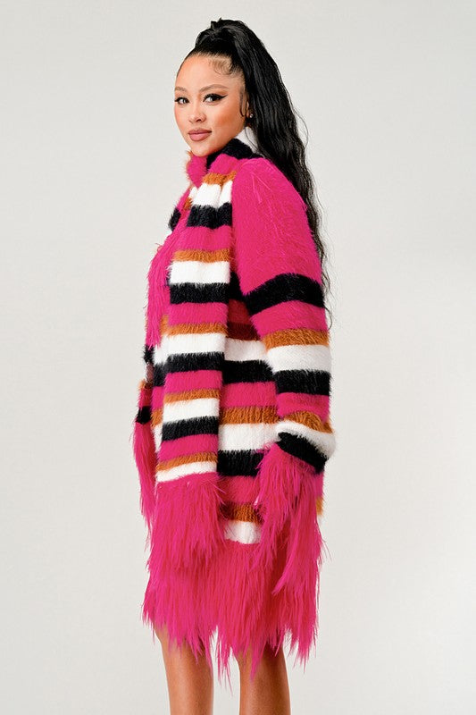 Woman wearing a colorful striped sweater with a pink fringe skirt on a white background
