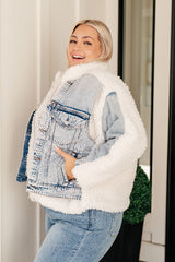 Woman wearing a denim jacket with white sherpa lining indoors.