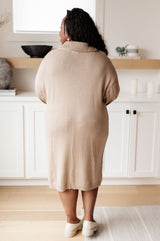 Person wearing a beige sweater standing in a kitchen.