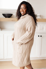 Woman wearing a beige cable knit sweater in a kitchen setting