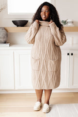 Woman wearing a beige cable knit dress in a kitchen setting