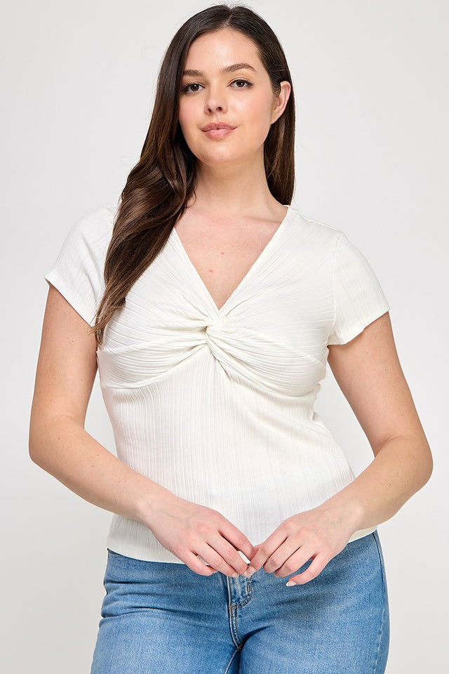 Woman wearing a white top with a knot detail and blue jeans on a white background