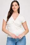 Woman wearing a white top with a knot detail and blue jeans on a white background