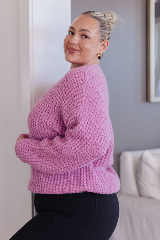 Woman wearing a pink knitted sweater in an indoor setting