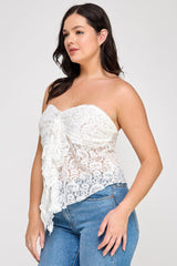 Woman wearing a white lace strapless top and blue jeans on a plain background