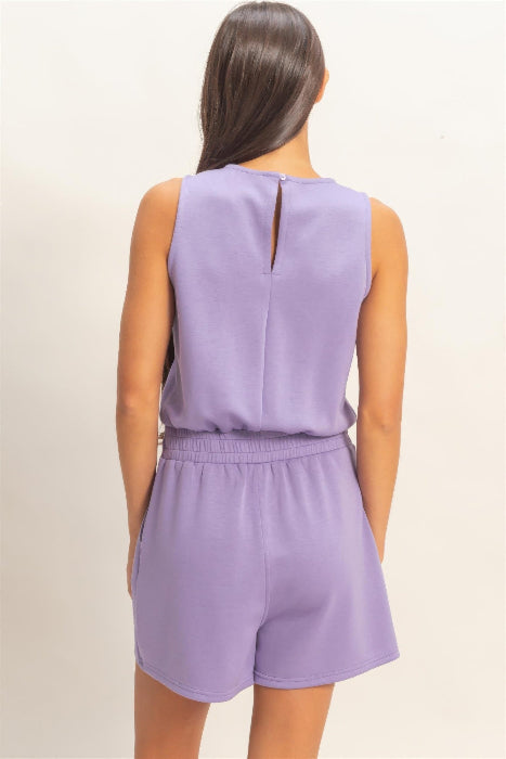 Person wearing a lavender romper on a beige background