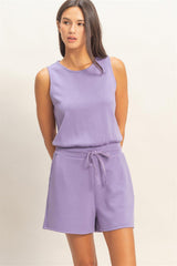 Woman wearing a purple Drawstring Waist Sleeveless Romper on a beige background