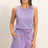 Woman wearing a lavender sleeveless romper on a plain background