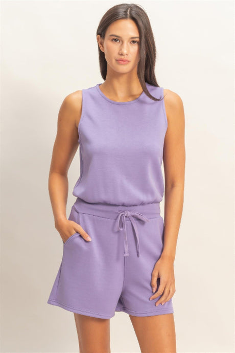 Woman wearing a lavender sleeveless romper on a plain background