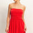 Woman wearing a strapless red romper against a plain background