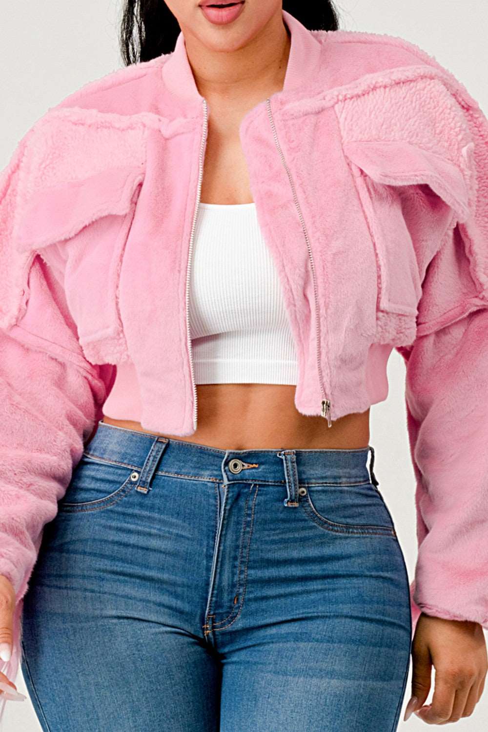 Person wearing a pink jacket and blue jeans against a white background