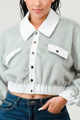 Person wearing a light gray jacket with white collar and buttons, paired with blue jeans.