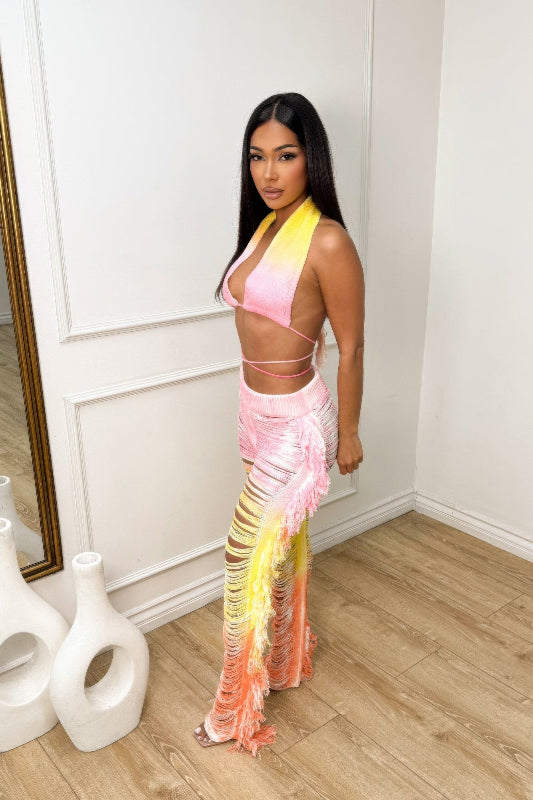 Woman wearing a colorful outfit standing in a room with white walls and wooden floor.