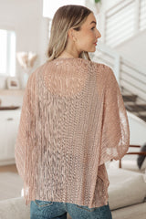 Woman wearing a beige knit cardigan in a bright room