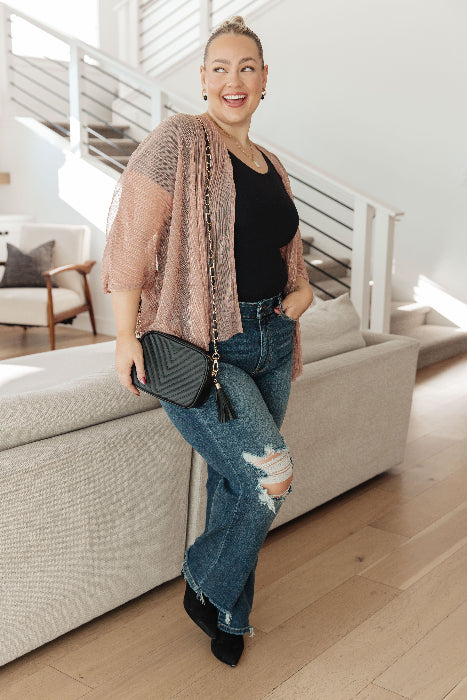 Woman standing in a modern living room holding a black handbag.