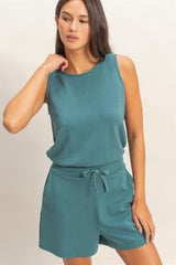 Woman wearing a teal Drawstring Waist Sleeveless Romper on a beige background