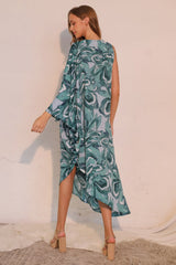 Woman wearing a blue and green patterned dress against a white background back view