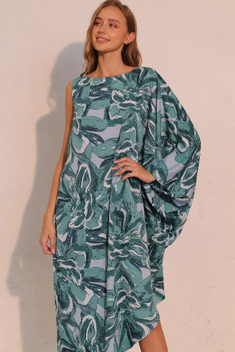 Woman wearing a green patterned dress against a plain background