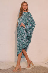 Woman wearing a green and blue patterned dress against a white background