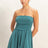 Woman wearing a teal strapless romper on a plain background