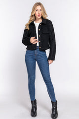Woman wearing a black jacket, white shirt, blue jeans, and black boots on a white background
