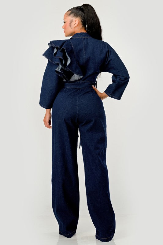 Person wearing a denim jumpsuit with ruffled details on a white background