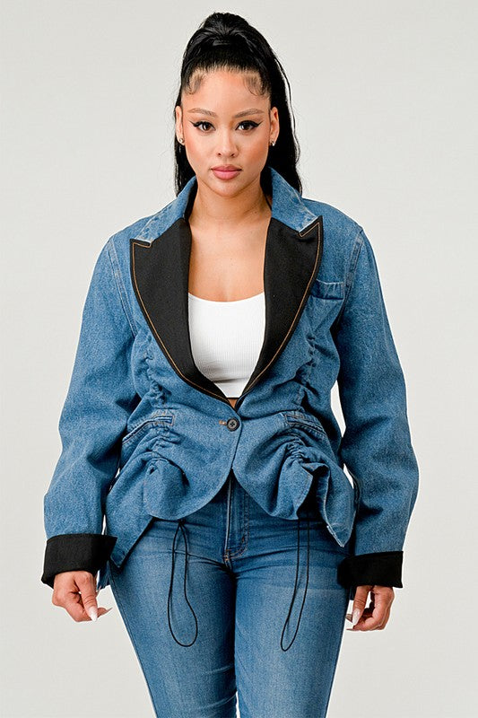 Woman wearing a blue denim jacket with black trim on a gray background