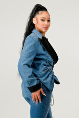 Woman wearing a blue denim jacket with black accents on a plain background