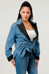 Woman wearing a denim jacket with black trim on a plain background