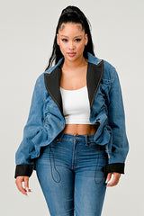 Woman wearing a blue denim jacket with black trim and jeans on a plain background