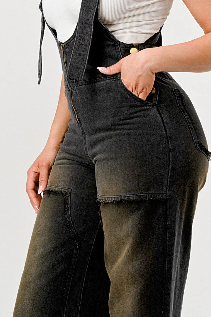 Person wearing black denim overalls on a plain background