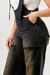 Person wearing black denim overalls on a plain background
