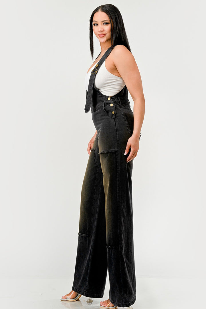 Woman wearing a black denim outfit with a white top on a plain background