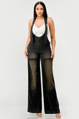 Woman wearing black denim overalls and a brown cowboy hat on a white background