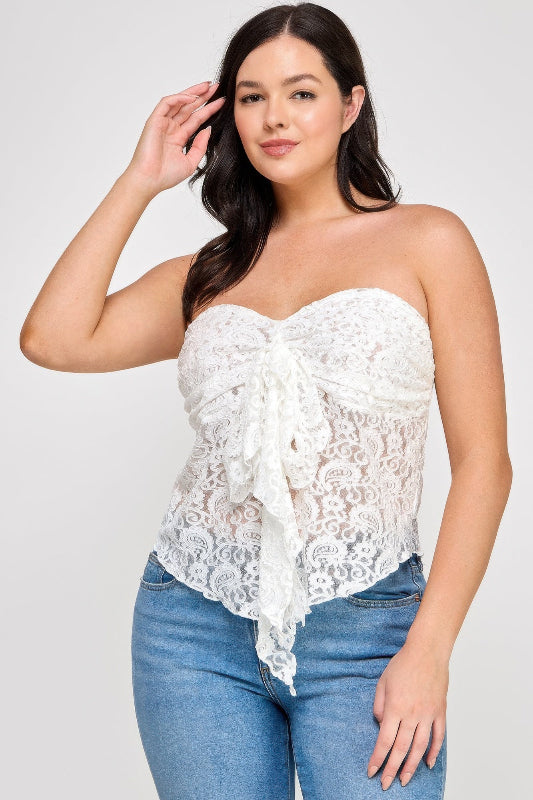Woman wearing a white lace strapless top and blue jeans on a plain background