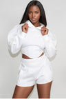 woman wearing a white hoodie and shorts set on a plain background