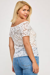 Woman wearing a white lace top and blue jeans on a plain background
