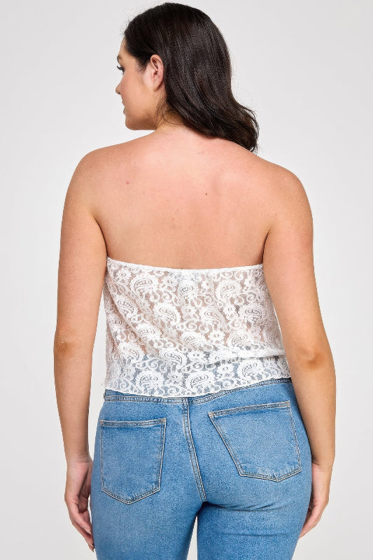 Woman wearing a white lace strapless top and blue jeans on a plain background