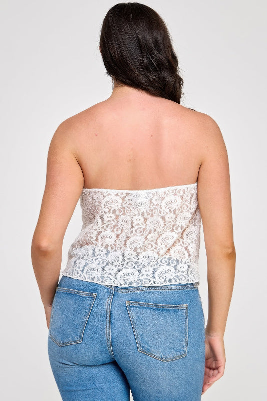 Woman wearing a white lace strapless top and blue jeans on a plain background