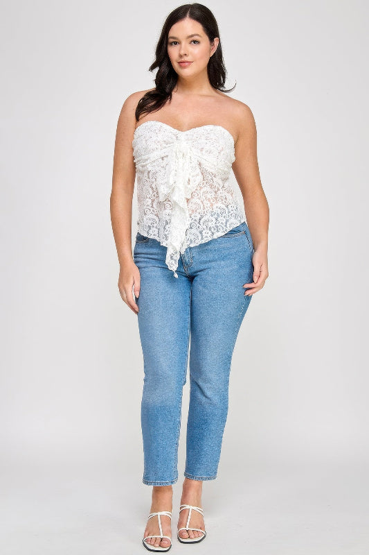Woman wearing a white lace top and blue jeans on a plain background