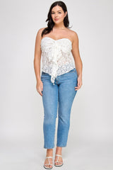 Woman wearing a white lace top and blue jeans on a plain background