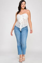 Woman wearing a white lace strapless top and blue jeans on a plain background