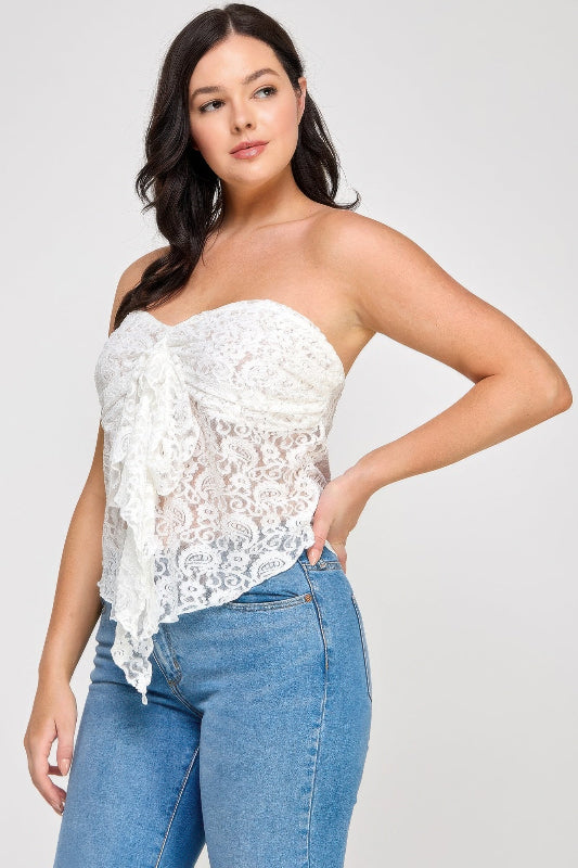 Woman wearing a white lace strapless top and blue jeans on a plain background