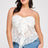 Woman wearing a white lace strapless top and blue jeans on a light gray background